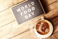 The cup of coffee and chalkboard with World Food Day text on wooden background Royalty Free Stock Photo