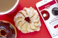 A cup of coffee with a Chocolate Dip Donut and Honey Cruller Donut with an iPhone Plus and the Tim Hortons app
