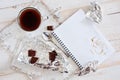 A cup of coffee, chocolate, a sheet of paper and a pen on a white wooden surface. Background for work at home in quarantine. The