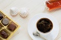 Cup of coffee, chocolates, meringue, handwork fruit jelly on a wooden background Royalty Free Stock Photo