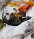 A cup of coffee, cinnamon bun and yellow leaves