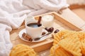 Cup of coffee with cinnamon and candle on rustic wooden serving tray in cozy bed with blanket. Knitting warm woolen Royalty Free Stock Photo