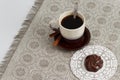 Cup of coffee with cinnamon and chocolate marsh-mallow on mat against monochromic tablecloth with copy space