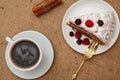 Cup of coffee, cinnamon, fork and slice of biscuit cake decorated with whipped cream and raspberries Royalty Free Stock Photo