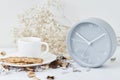 Cup of coffee and classic alarm clock on a white table. Autumn or winter cozy background. Hygge style