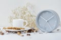 Cup of coffee and classic alarm clock on a white table. Autumn or winter cozy background. Hygge style Royalty Free Stock Photo