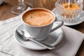 Cup of coffee close-up with spoon, saucer and brown sugar bowl on wooden table