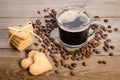 The cup of coffee, coffee beans and cookies-hearts related together on wooden table Royalty Free Stock Photo