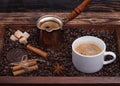 Cup of coffee, coffeepot, biscuit, cinnamon, anise, sugar, coffee beans on wooden tray