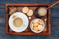 Cup of coffee, coffeepot, cinnamon, anise, sugar, cookies on a wooden tray.