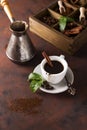 Cup of coffee with cooffee beans, wooden box with grains of coffee and spices, cezve on a stone background Royalty Free Stock Photo