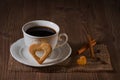 A cup of coffee and cookies like heart, cinnamon, coffee beans on wooden table on dark background Royalty Free Stock Photo