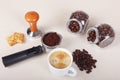 Cup of coffee, crackers, holder with ground coffee, tamper and cans of coffee beans on table Royalty Free Stock Photo