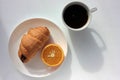 Cup of coffee, croissant and orange on white background. Top view, copy space. Morning espresso on table. Healthy breakfast. Royalty Free Stock Photo