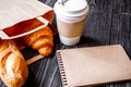 Cup coffee and croissant in paper bag on wooden background Royalty Free Stock Photo