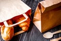 Cup coffee and croissant in paper bag on wooden background Royalty Free Stock Photo