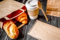 Cup coffee and croissant in paper bag on wooden background Royalty Free Stock Photo