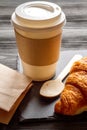 Cup coffee and croissant in paper bag on wooden background Royalty Free Stock Photo