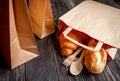 Cup coffee and croissant in paper bag on wooden background Royalty Free Stock Photo