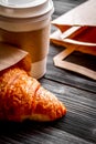 Cup coffee and croissant in paper bag on wooden background Royalty Free Stock Photo