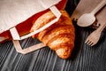 Cup coffee and croissant in paper bag on wooden background Royalty Free Stock Photo