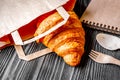 Cup coffee and croissant in paper bag on wooden background Royalty Free Stock Photo