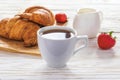 Cup of coffee, croissants, strawberry and milk jar