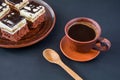 A cup of coffee on a dark table and pieces of delicious chocolate cake with cream and chocolate fondant on a plate Royalty Free Stock Photo
