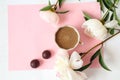A Cup of coffee with delicate peonies and two chocolates on a rose background, top view-a place for text-the concept of a pleasant