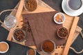 A cup of coffee, different types of coffee and sugar in cups on a brown background.