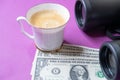 Cup of coffee, dollar bills and binoculars symbolize discernment in financial transactions