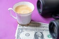 Cup of coffee, dollar bills and binoculars symbolize discernment in financial transactions Royalty Free Stock Photo