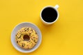 Cup of coffee and a donut on colored yellow background. Top view, copy space. Royalty Free Stock Photo