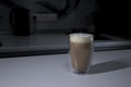 Cup of coffee in a double-botoom glass on white table in gray kitchen