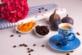 A cup of coffee, dried apricots and cranberries, fresh figs, a hydrangea branch and sprinkled coffee beans
