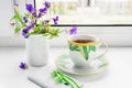 A cup of coffee, flowers of the field pansies, phone and headphones on the windowsill Royalty Free Stock Photo