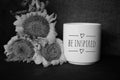 Cup of coffee and flowers. With inspirational note - Be inspired in black and white background Royalty Free Stock Photo