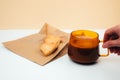 A cup of coffee with foam in female hand and a plate with heart-shaped shortbread cookies on a paper bag Royalty Free Stock Photo