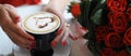 A cup of coffee with foam in the foreground a heart is drawn. The hands of a woman with red nail polish holds her Royalty Free Stock Photo