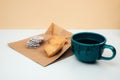 A cup of coffee with foam and a plate with heart-shaped shortbread cookies and chocolate rounds on a paper bag Royalty Free Stock Photo