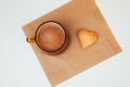 A cup of coffee with foam and a plate with heart-shaped shortbread cookies on a paper bag Royalty Free Stock Photo