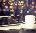 Cup of coffee in front of digital tablet pc near window, vintage style