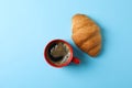 Cup of coffee with frothy foam and croissant on color background, space for text and top view Royalty Free Stock Photo