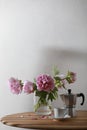 Cup of coffee, geyser coffee maker and bunch of peony flowers on wooden table. Copy space Royalty Free Stock Photo