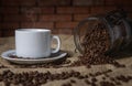 Cup of coffee and a glass jar with coffee beans scattered on the table Royalty Free Stock Photo