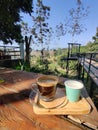 A cup of coffee with a glass of water at the outside building with natural view.