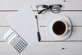 A cup of coffee, glasses, calculator and empty paper for your te