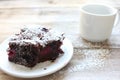 Cup of coffee with handmade chocolate cake on wooden table background. Brownie with cherries on a white plate. Royalty Free Stock Photo