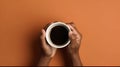 A cup of coffee in the hands of an African-American man on a brown background, with a place for text, top view Royalty Free Stock Photo