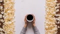 Cup of coffee in hands on table. Rose petals. Flatlay